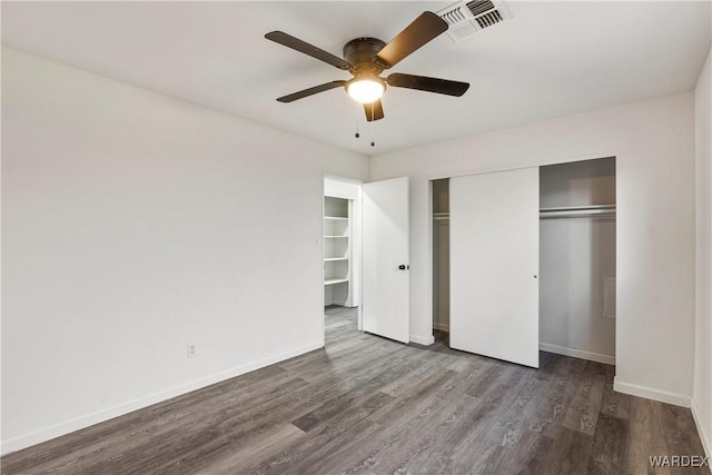 unfurnished bedroom with dark wood-style floors, a closet, visible vents, and baseboards