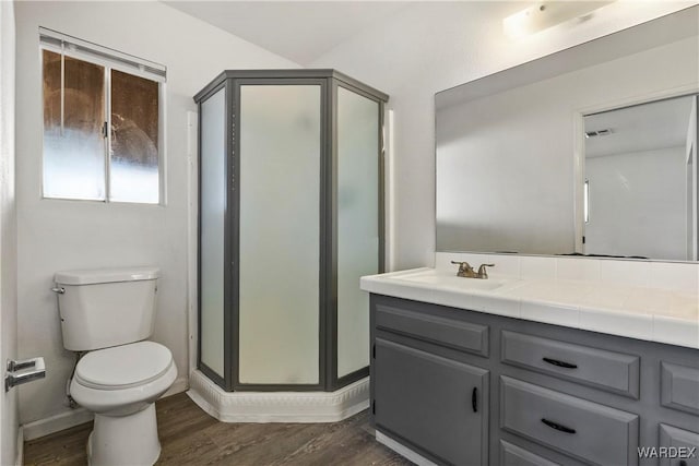 full bathroom featuring a stall shower, baseboards, toilet, wood finished floors, and vanity