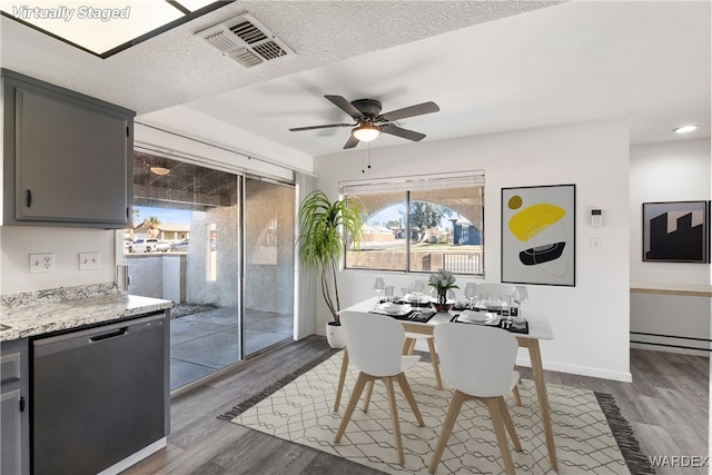 dining area featuring a textured ceiling, dark wood-type flooring, visible vents, and baseboards