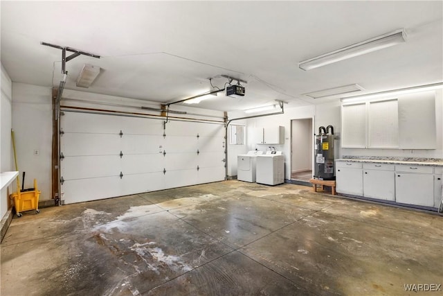 garage featuring electric water heater, separate washer and dryer, and a garage door opener