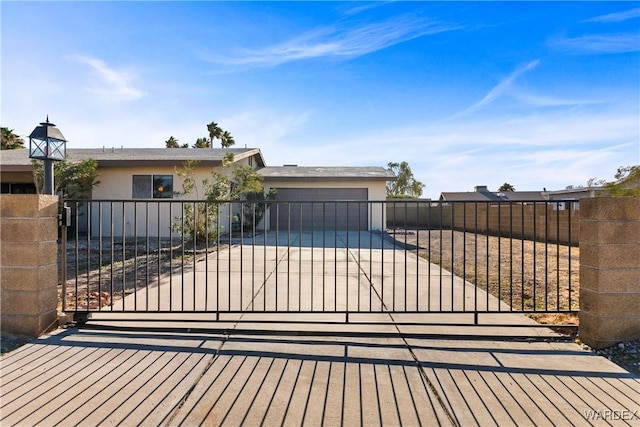 view of front facade with driveway, a garage, fence, and stucco siding