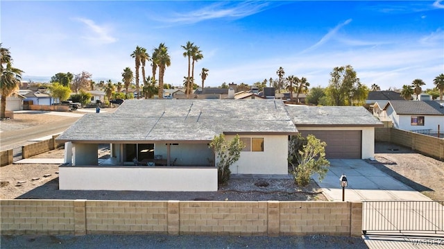 view of front of house featuring driveway, a residential view, an attached garage, fence private yard, and stucco siding