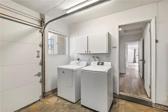 laundry room featuring a garage, cabinet space, and separate washer and dryer