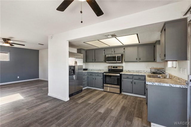 kitchen with a sink, stainless steel appliances, light countertops, and gray cabinetry