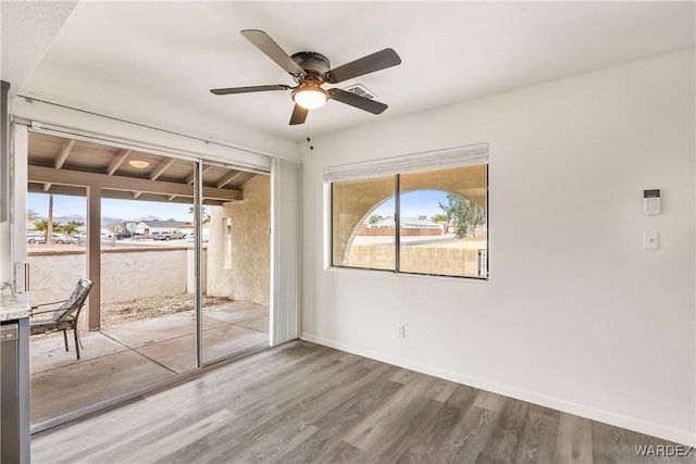 interior space featuring a ceiling fan, visible vents, baseboards, and wood finished floors