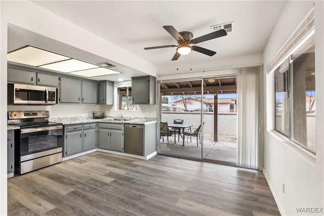 kitchen with dark wood-style floors, stainless steel appliances, visible vents, and gray cabinetry