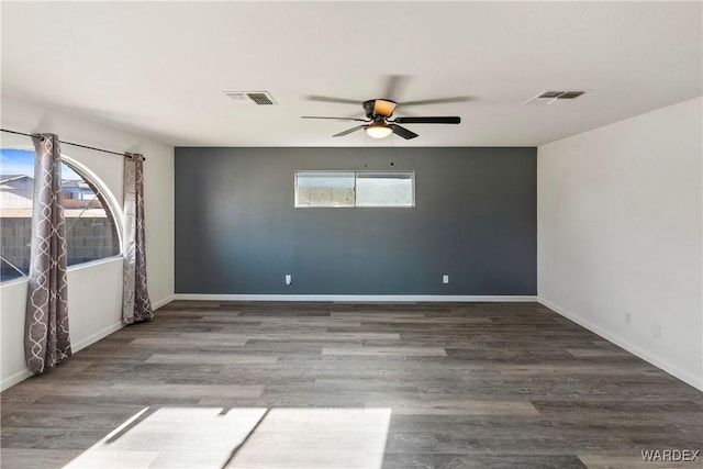 empty room with baseboards, visible vents, and wood finished floors