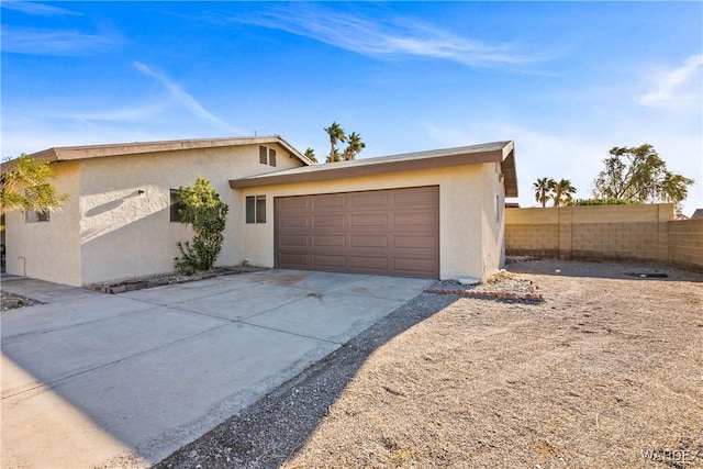 view of front of property featuring an attached garage, fence, concrete driveway, and stucco siding