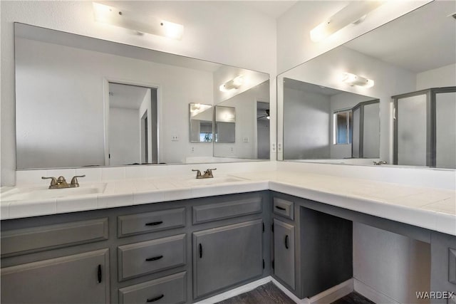 bathroom with double vanity, a stall shower, and a sink