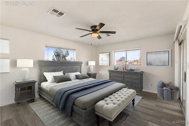 bedroom with dark wood-type flooring, multiple windows, visible vents, and baseboards