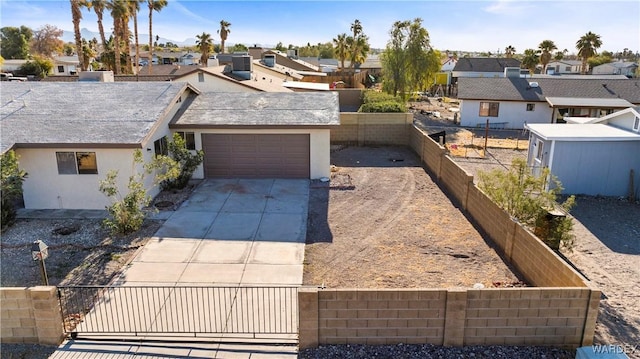 view of front facade with an attached garage, fence private yard, concrete driveway, a residential view, and stucco siding