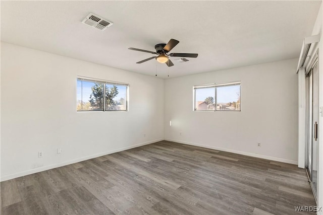 interior space featuring dark wood-type flooring, a wealth of natural light, visible vents, and baseboards