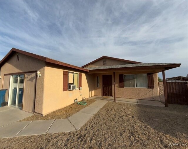 ranch-style home with cooling unit, fence, and stucco siding