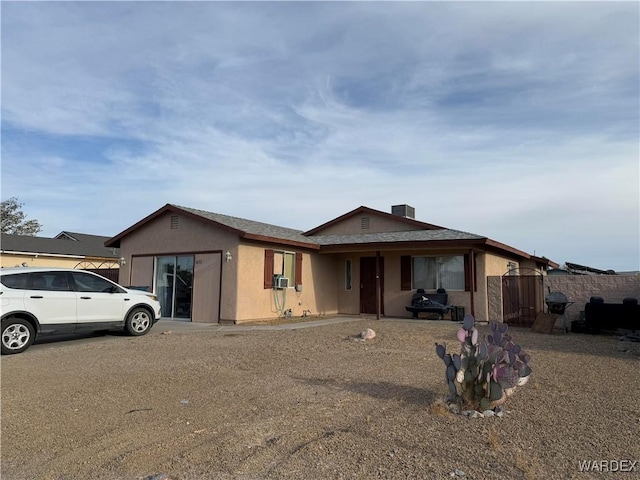 ranch-style home featuring fence, an attached garage, cooling unit, and stucco siding