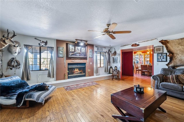 4390 El Camino Rd, Bullhead City, AZ 86429 - living area with a textured ceiling, ceiling fan, a glass covered fireplace, and hardwood / wood-style flooring