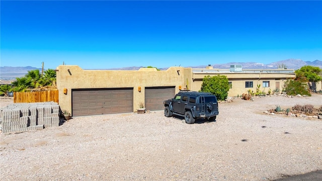 4390 El Camino Rd, Bullhead City, AZ 86429 - pueblo-style home featuring a mountain view, a garage, stucco siding, and gravel driveway