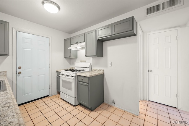 kitchen with under cabinet range hood, visible vents, gray cabinets, and gas range gas stove