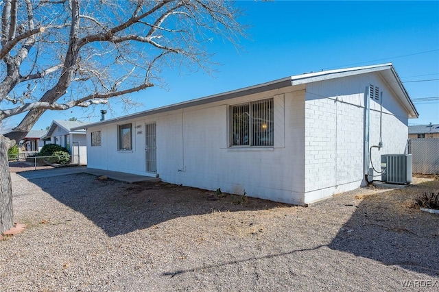 exterior space with cooling unit, concrete block siding, and fence