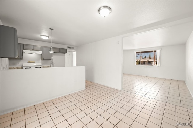 kitchen with gray cabinetry, under cabinet range hood, stove, a sink, and light countertops