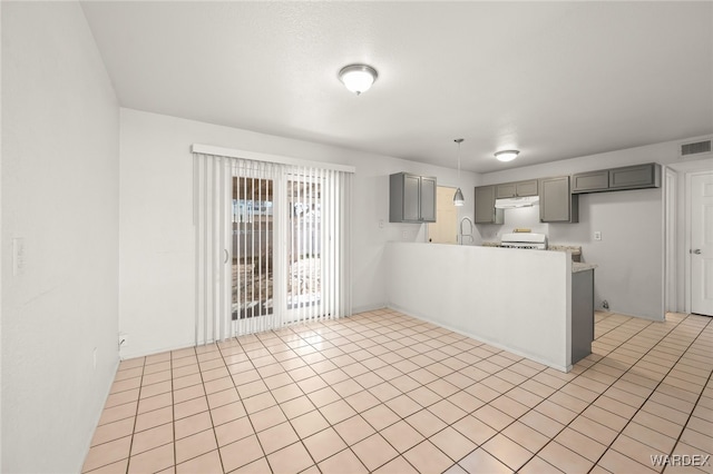 kitchen featuring light tile patterned floors, gray cabinets, light countertops, visible vents, and under cabinet range hood