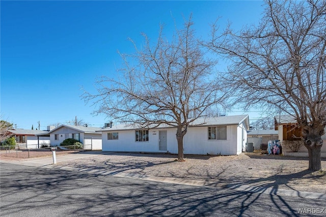 single story home featuring concrete driveway, fence, and central air condition unit