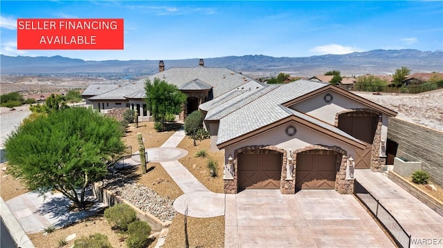 view of front facade featuring an attached garage, stone siding, driveway, and a mountain view