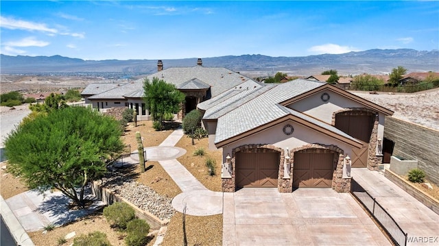 view of front of home with stone siding, a mountain view, driveway, and an attached garage