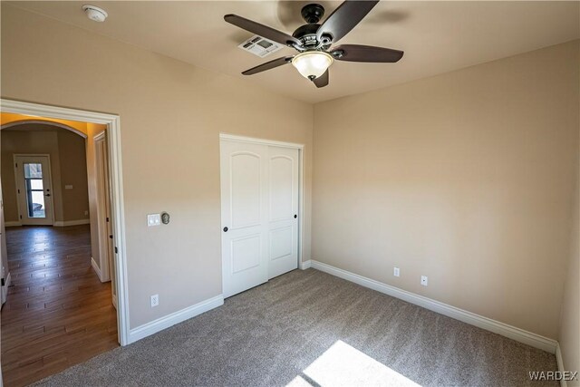 unfurnished bedroom with arched walkways, a closet, visible vents, a ceiling fan, and baseboards