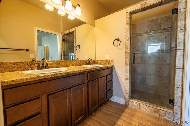 bathroom featuring double vanity, a stall shower, and a sink