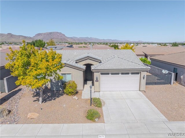 single story home with a garage, driveway, fence, a mountain view, and stucco siding