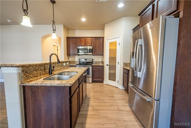 kitchen with light wood-style flooring, hanging light fixtures, stainless steel appliances, a sink, and recessed lighting