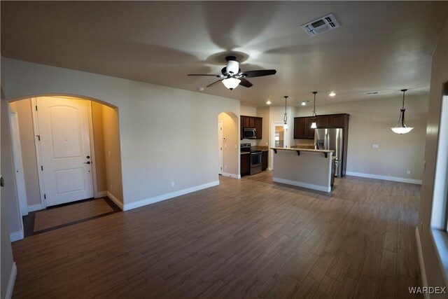 unfurnished living room featuring visible vents, arched walkways, a ceiling fan, baseboards, and dark wood-type flooring