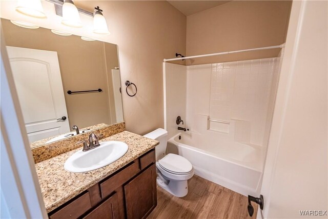 full bath with vanity, shower / washtub combination, wood finished floors, and toilet