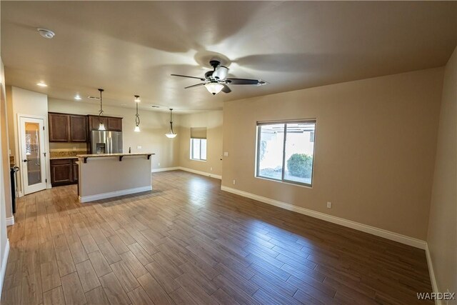 kitchen with a kitchen island, open floor plan, light countertops, stainless steel fridge, and decorative light fixtures