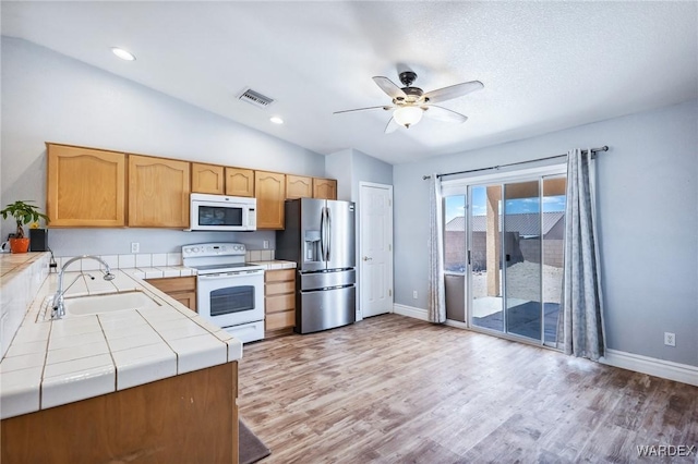 4403 S Via Rialto Ln, Fort Mohave, AZ 86426 - kitchen with white appliances, baseboards, tile counters, a sink, and vaulted ceiling