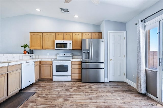 4403 S Via Rialto Ln, Fort Mohave, AZ 86426 - kitchen with visible vents, lofted ceiling, white appliances, tile counters, and light wood-style flooring