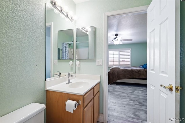 4403 S Via Rialto Ln, Fort Mohave, AZ 86426 - ensuite bathroom featuring a textured wall, ceiling fan, vanity, toilet, and wood finished floors