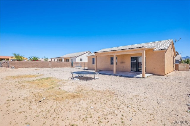 4403 S Via Rialto Ln, Fort Mohave, AZ 86426 - back of property with a trampoline, stucco siding, a fenced backyard, a patio area, and a tiled roof