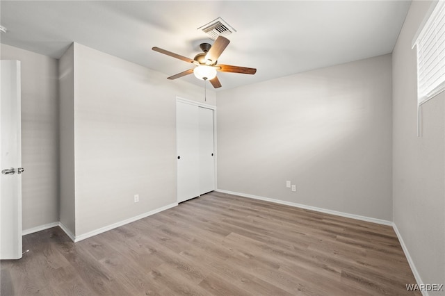 unfurnished bedroom featuring a ceiling fan, baseboards, visible vents, and wood finished floors