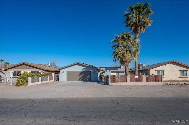 ranch-style house with a fenced front yard, concrete driveway, a garage, and solar panels