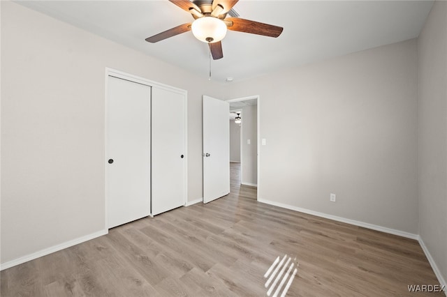 unfurnished bedroom with ceiling fan, a closet, light wood-style flooring, and baseboards