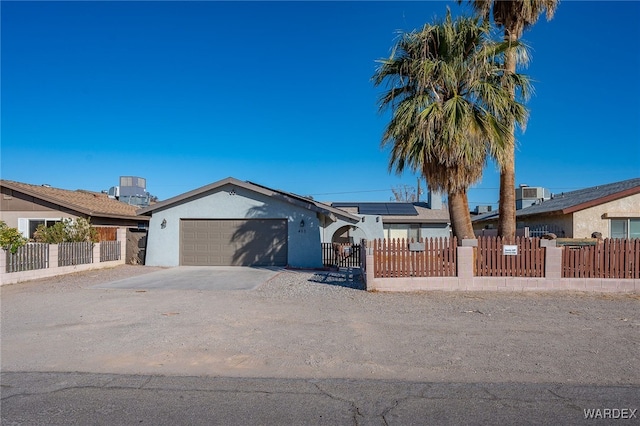 single story home featuring an attached garage, a fenced front yard, roof mounted solar panels, and concrete driveway