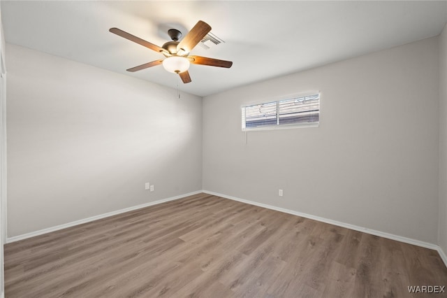 empty room featuring visible vents, wood finished floors, a ceiling fan, and baseboards