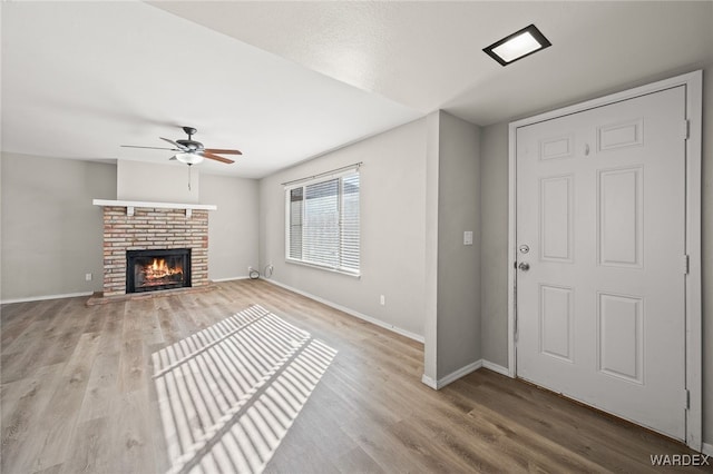 unfurnished living room featuring baseboards, a fireplace, and light wood-style floors