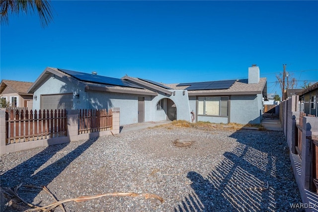 single story home with a garage, solar panels, a chimney, fence private yard, and stucco siding