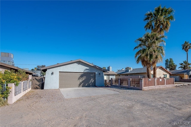 single story home with concrete driveway, a fenced front yard, an attached garage, and stucco siding