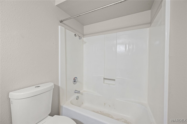 full bath featuring toilet, a textured wall, and shower / bathtub combination