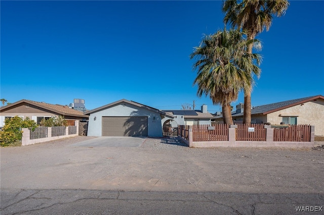 single story home with a fenced front yard, a garage, solar panels, driveway, and stucco siding