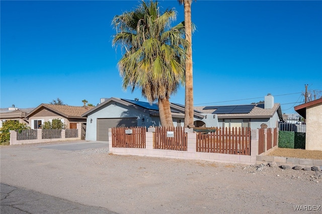 ranch-style house with a fenced front yard, stucco siding, concrete driveway, an attached garage, and roof mounted solar panels