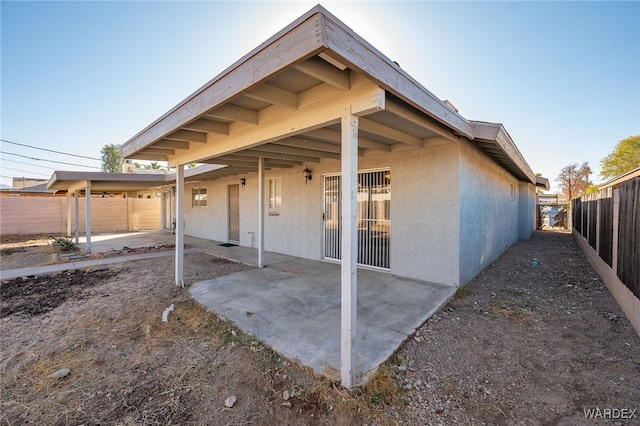 view of side of property featuring a patio area, a fenced backyard, and stucco siding